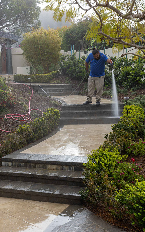 pressure washing professional in blue shirt washing concrete steps